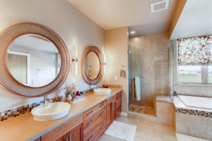 designer master bathroom with tub, shower, mirrors, lighting, and vanity