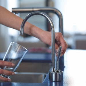 person filling up cup of water from an immerse luxury kitchen faucet